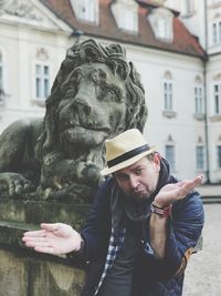 Portrait of man standing by statue in city