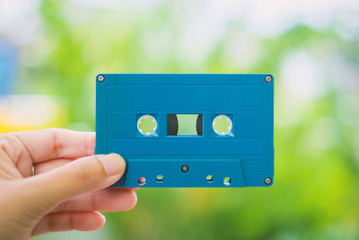 Close-up of hand holding blue audio cassette