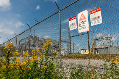 Information sign on fence against sky