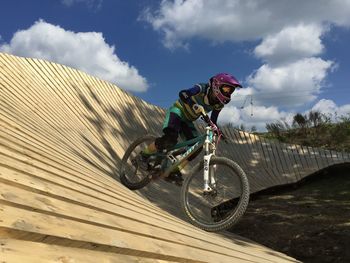 Man riding bicycle in bikepark against sky