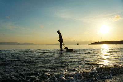 A woman and puppy playing at the beach