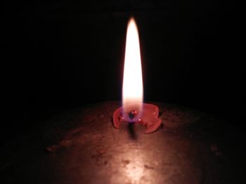 Close-up of illuminated candle in darkroom