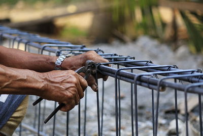 Cropped hands of man holding metal with hand tool