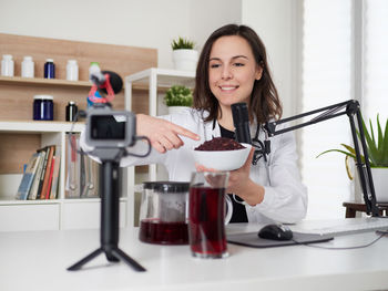 Portrait of young woman using mobile phone at table