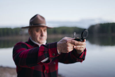 Bushcrafter holding navigational compass while hiking in forest