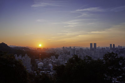 Buildings in city against sky during sunset