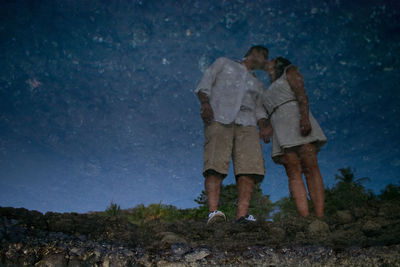 Couple reflecting in lake while kissing at dusk