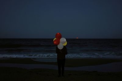 Man holding balloons and standing at beach