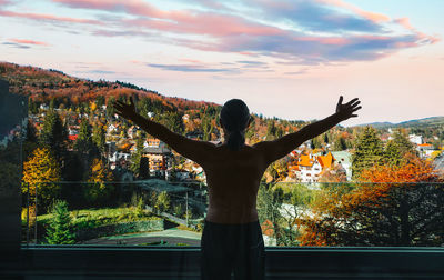 Man in balcony against mountain town in autumn morning