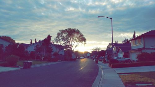 Road amidst houses in town against sky