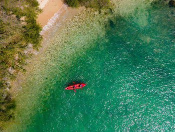 The top view of two tourist paddling their red kayak at the beautiful blue seashore in summer