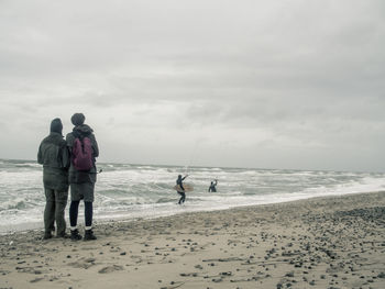 People standing on beach against sky