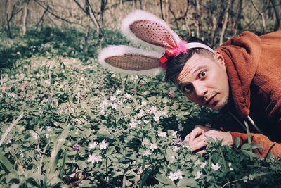 Portrait of young man wearing bunny ear headband in park
