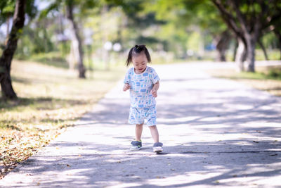 Full length of girl walking on footpath against trees