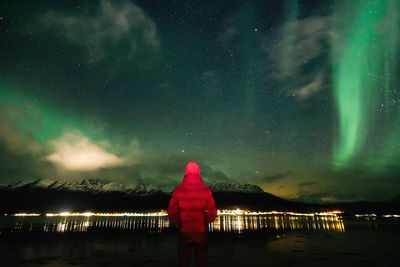Rear view of man looking at aurora borealis