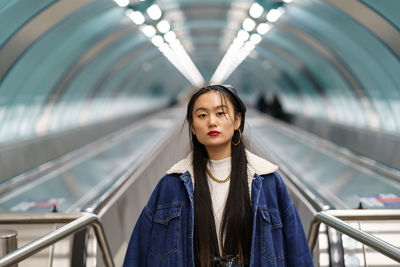 Asian girl street fashion look, stylish female wearing leather beret on escalator ride to subway