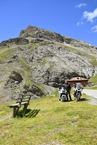 Man with motor scooter standing on field against mountains