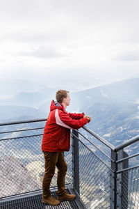 Man standing on railing against mountain