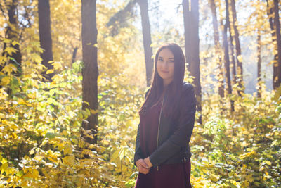 Young woman standing amidst trees in forest