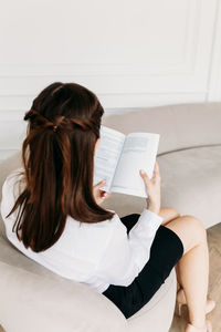 Midsection of woman reading book at home