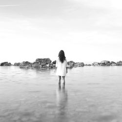 Rear view of woman standing in sea against sky