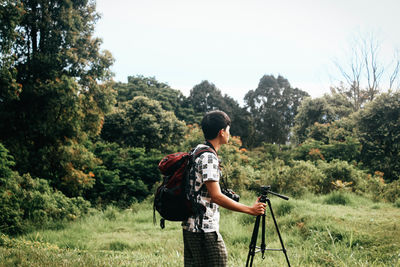 Rear view of man photographing on field