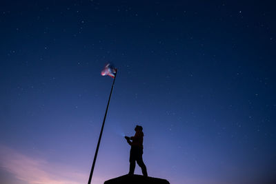 Man shines a flashlight to the thai flag on the mountain in the morning and evening