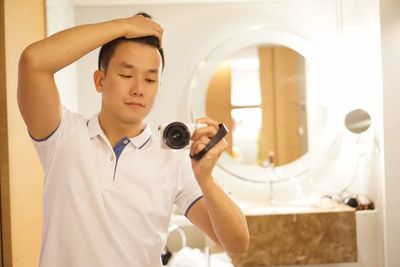 Young man photographing with digital camera at home