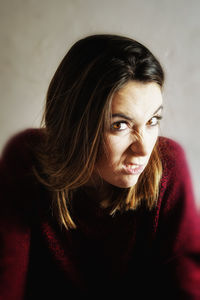 Close-up portrait of beautiful young woman making face against wall