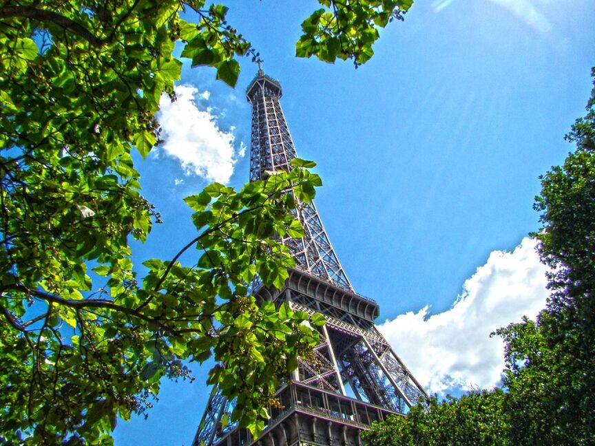 low angle view, tall - high, built structure, tree, architecture, tower, famous place, travel destinations, international landmark, tourism, eiffel tower, sky, skyscraper, modern, capital cities, building exterior, travel, city, blue, growth