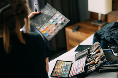 Rear view of woman holding make up palette in room