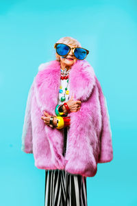 Senior woman wearing sunglasses against blue background