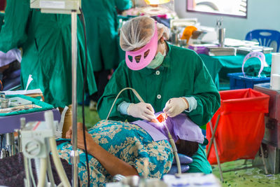 Male dentist operating female patient in hospital