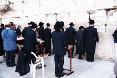 Rear view of people standing against wall