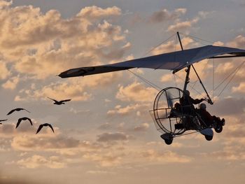 Low angle view of airplane flying against sky during sunset