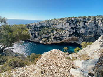 Panoramic view of rocks and sea against clear blue sky