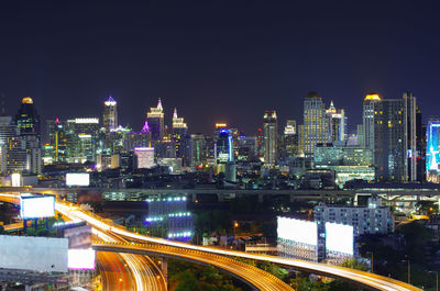 Illuminated modern buildings in city against sky at night