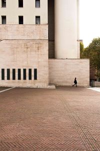 Woman walking on footpath against building