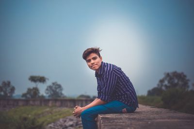 Portrait of young man standing against blue sky