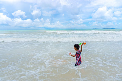 Full length of child on beach against sky