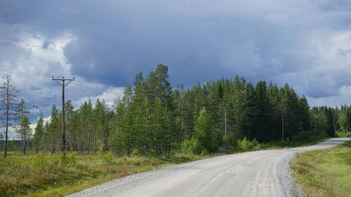 Road by trees against sky