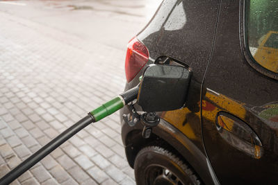 An open tank with a fuel hose at a gas station in a black car