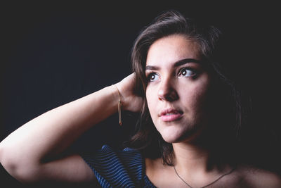 Close-up of young woman against black background