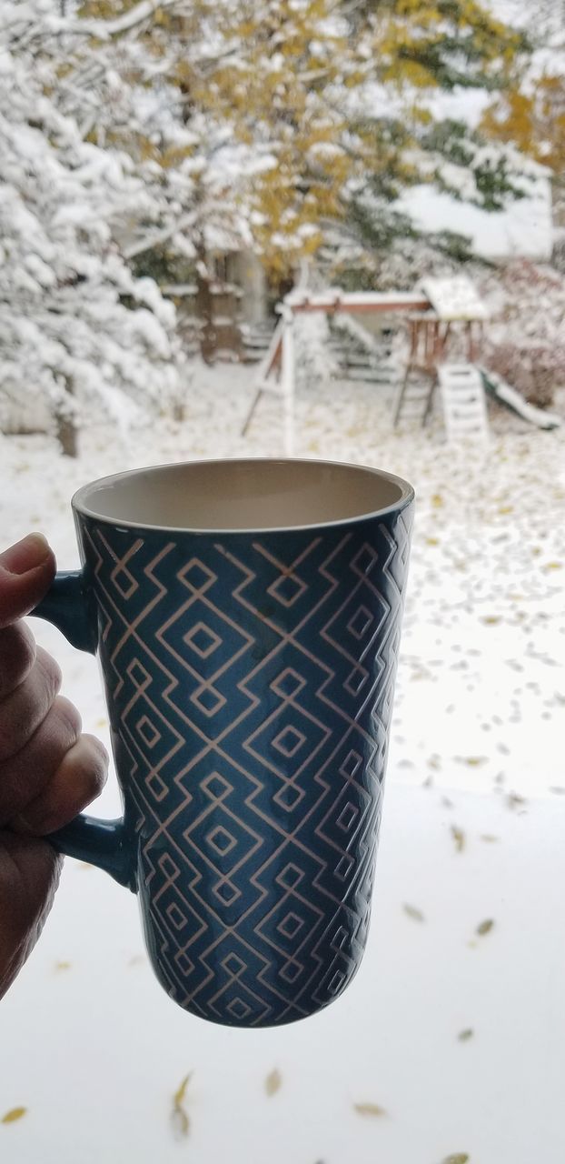 CLOSE-UP OF PERSON HAND HOLDING COFFEE CUP WITH ICE CREAM