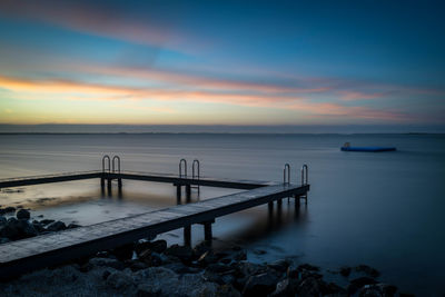 Pier over sea against sky during sunset