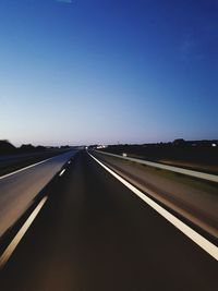 Empty road against clear blue sky