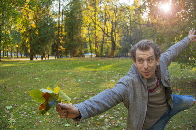 Portrait of smiling young woman with autumn leaves in park