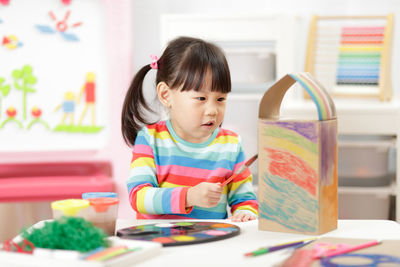 Girl painting cardboard box at home