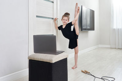 Full length portrait of girl standing against wall at home