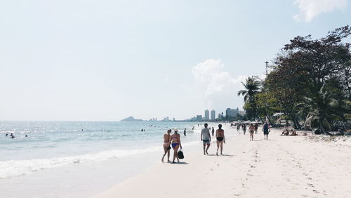 People walking at beach by sea against sky